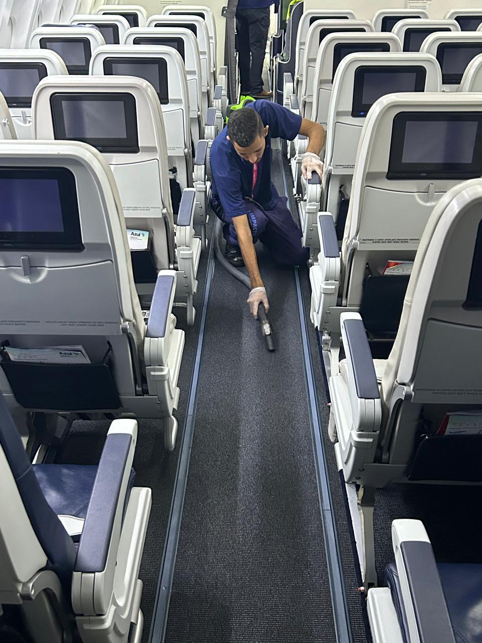Impacto Aviation technician vacuuming the cabin aisle
